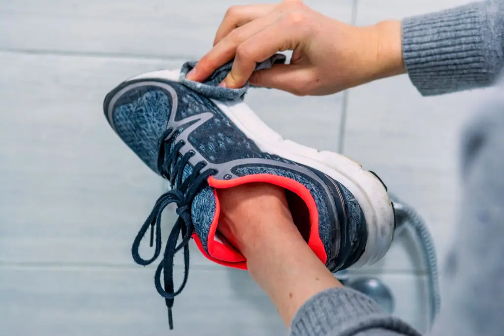 Una persona limpia a mano unas zapatillas de deporte