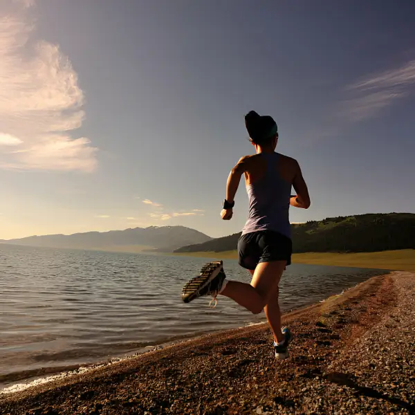 Una mujer haciendo trail running a la orilla de un lago 