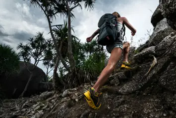 Una mujer haciendo trekking con unas zapatillas verdes y amarillas